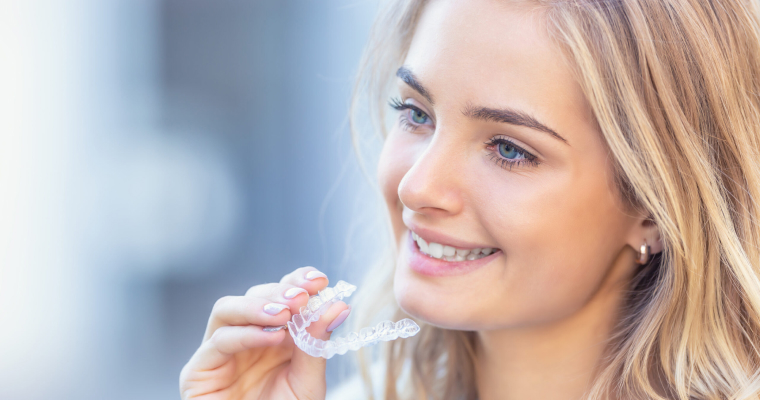 Young lady holding Invisalign aligner tray